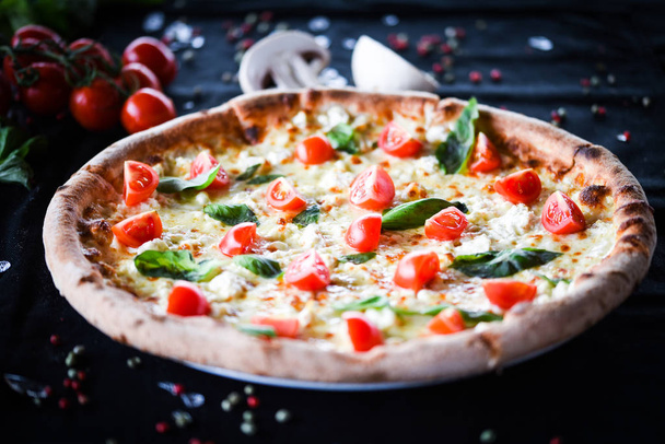 ízletes olasz pizza cseresznyés paradicsommal, friss bazsalikom és gorgonzola sajt - Fotó, kép