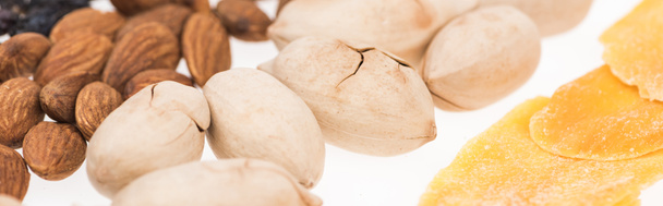 close up view of pistachio nuts, almonds and dried mango isolated on white, panoramic shot - Foto, Imagen