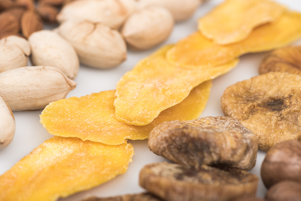 zblízka pohled na pistáciové ořechy, sušené mango a fíky izolované na bílém - Fotografie, Obrázek