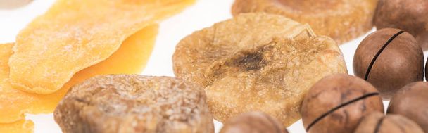 close up view of dried mango slices, figs and macadamia nuts isolated on white, panoramic shot - Fotografie, Obrázek