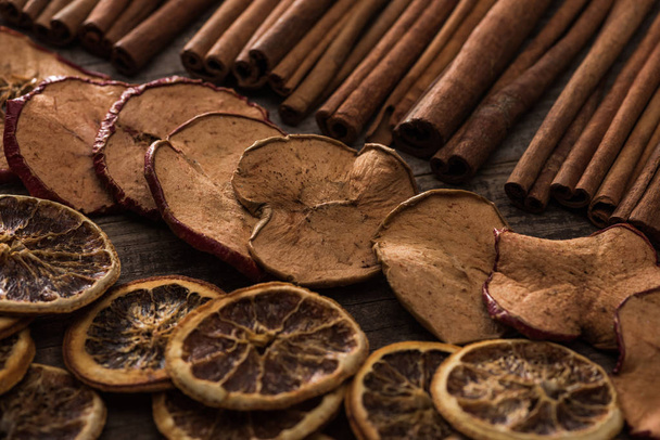 dried orange and apple slices with cinnamon on wooden background - 写真・画像