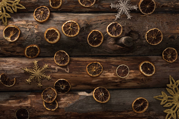 vista superior de fatias de citrinos secos e flocos de neve decorativos em fundo de madeira
 - Foto, Imagem