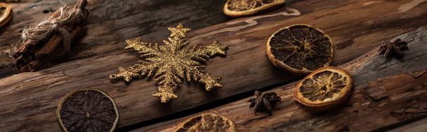 dried citrus slices with anise, cinnamon sticks and decorative snowflake on wooden background, panoramic shot - Photo, image