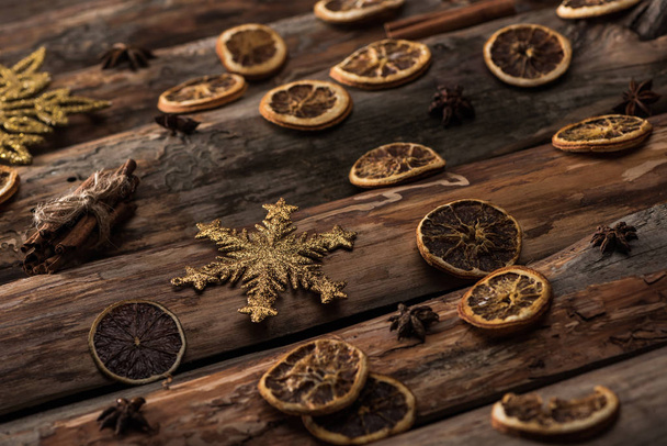 fatias de citrinos secos com anis, paus de canela e flocos de neve decorativos no fundo de madeira
 - Foto, Imagem
