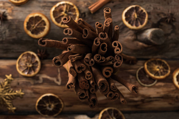 top view of dried citrus slices with cinnamon sticks and decorative snowflakes on wooden background - 写真・画像