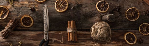 plat gelegd met kaneelstokjes, schaar, draadbal op houten ondergrond met winterdecor, panoramisch schot - Foto, afbeelding