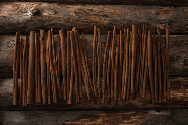 top view of cinnamon sticks on wooden background - Foto, imagen