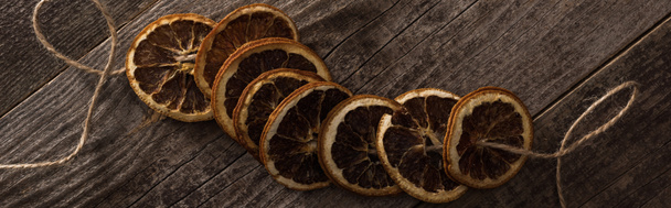 pohled shora na sušené oranžové plátky na laně na dřevěném povrchu, panoramatický záběr - Fotografie, Obrázek
