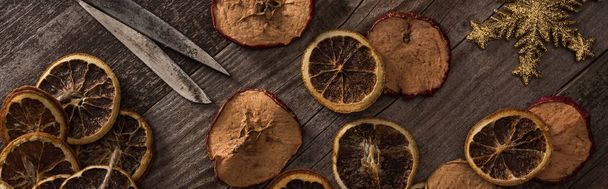 vrchní pohled na sušené citrusy a jablečné plátky u sněhové vločky, lano a nůžky na dřevěném povrchu, panoramatický výstřel - Fotografie, Obrázek