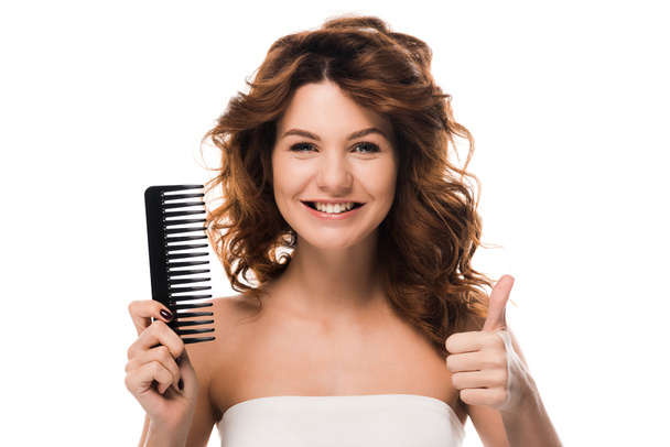 menina feliz com cabelo encaracolado segurando escova de cabelo e mostrando polegar para cima isolado no branco
  - Foto, Imagem