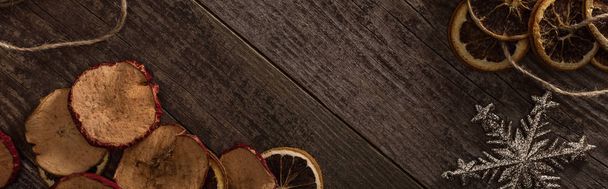 top view of dried citrus and apple slices near snowflake on wooden surface with copy space, panoramic shot - Zdjęcie, obraz