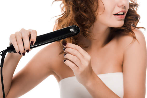 cropped view of surprised curly woman using hair straightener isolated on white   - Fotó, kép