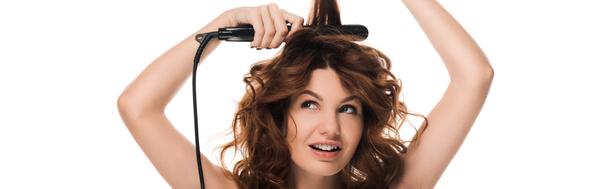 panoramic shot of curly woman using hair straightener isolated on white   - Photo, Image