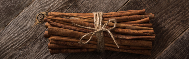 top view of cinnamon sticks in bunch on wooden rustic table, panoramic shot - Fotografie, Obrázek