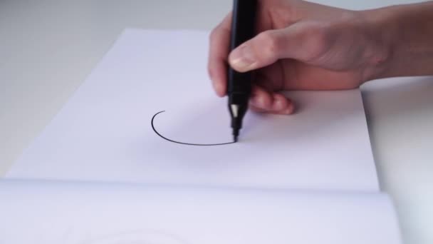 Hand of a teenager draws with felt-tip pen on a white blank sheet of an album. The concept of creative tasks in education - Кадри, відео