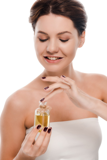 veselá žena při pohledu na láhev s olejem izolované na bílém  - Fotografie, Obrázek