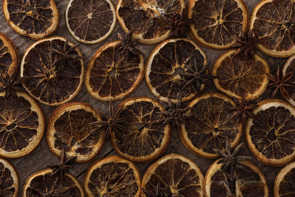 horní pohled na sušené pomerančové plátky na dřevěném pozadí s anýzem - Fotografie, Obrázek