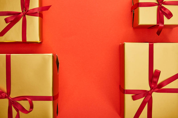 flat lay with golden gift boxes on red background with copy space - Fotó, kép