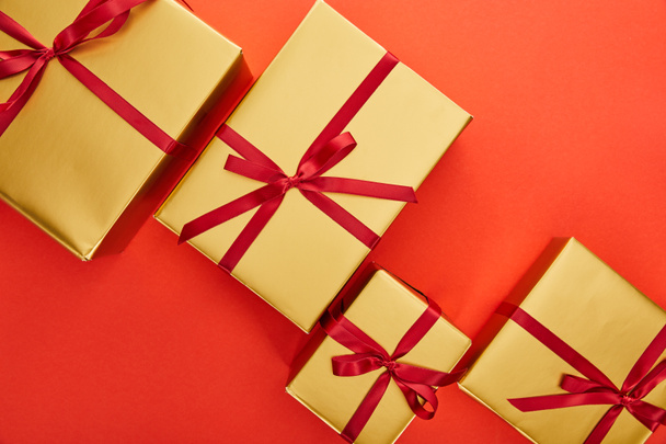 Ansicht der goldenen Geschenkboxen auf rotem Hintergrund - Foto, Bild