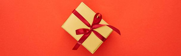 Kırmızı arkaplanda altın hediye kutusunun üst görünümü, panoramik çekim - Fotoğraf, Görsel