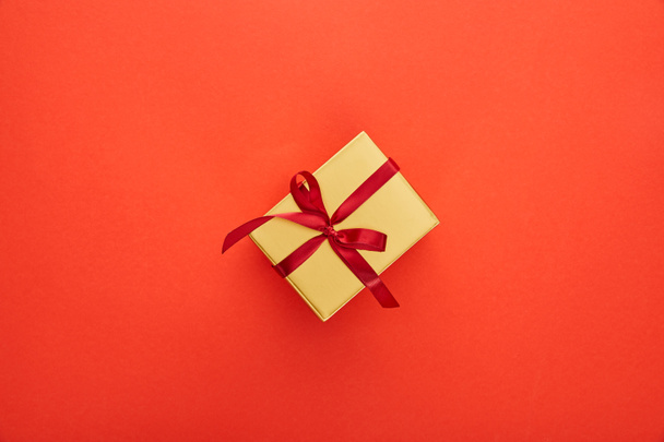 top view of golden gift box on red background - Foto, Imagem