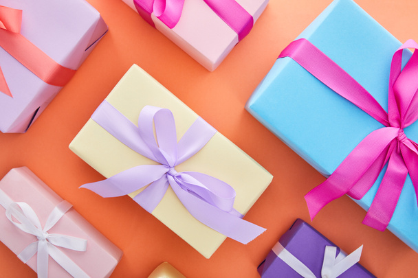 flat lay with multicolored gift boxes with ribbons and bows on orange background - Foto, Imagem