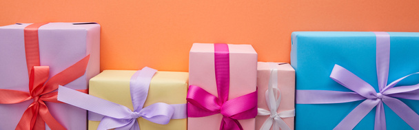 επίπεδο θέσει με πολύχρωμα κουτιά δώρων με κορδέλες και φιόγκους σε πορτοκαλί φόντο, πανοραμική λήψη - Φωτογραφία, εικόνα