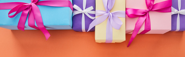 flat lay with multicolored gift boxes with ribbons and bows on orange background with copy space, panoramic shot - Photo, Image
