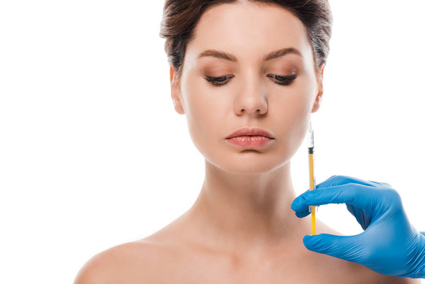 vista recortada de cirurgião plástico em seringa luva de látex azul segurando perto atraente paciente nu isolado em branco
  - Foto, Imagem