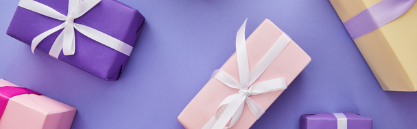 top view of colorful presents with bows scattered on purple background, panoramic shot - Φωτογραφία, εικόνα