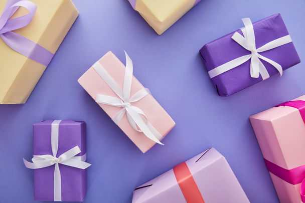 Draufsicht auf bunte Geschenke mit Schleifen auf violettem Hintergrund - Foto, Bild