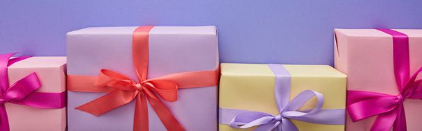 紫色の背景に弓でカラフルなプレゼントとフラットレイ、パノラマショット - 写真・画像