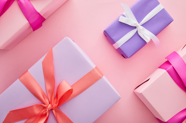 flat lay with colorful gift boxes with ribbons and bows scattered on pink background - Fotografie, Obrázek