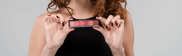 panoramic shot of woman holding eye shadow isolated on grey  - Foto, afbeelding
