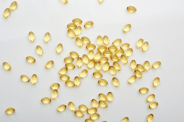 top view of golden fish oil capsules scattered on white background - Photo, Image