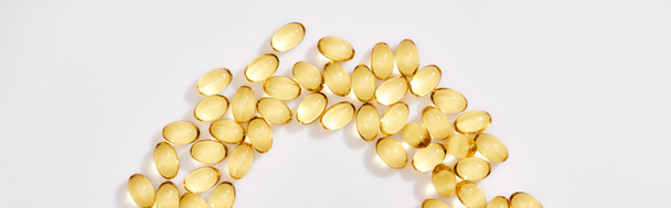 κορυφαία άποψη του χρυσαφί κάψουλες ιχθυέλαιο τοποθετημένα στο μισό στρογγυλό πλαίσιο σε λευκό φόντο, πανοραμική λήψη - Φωτογραφία, εικόνα