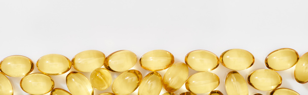 flat lay with golden fish oil capsules on white background, panoramic shot - 写真・画像