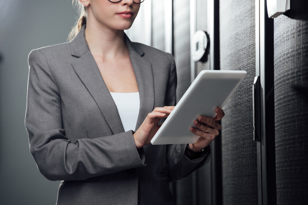 cropped view of businesswoman holding digital tablet in server room  - Foto, afbeelding