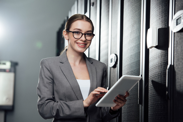 selective focus of cheerful businesswoman holding digital tablet in server room  - Photo, Image