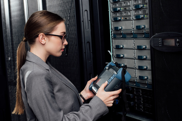 side view of businesswoman holding reflectometer in data center  - Photo, Image