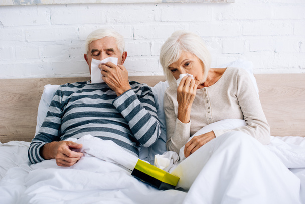 mari malade et femme éternuant et tenant des serviettes dans l'appartement
  - Photo, image