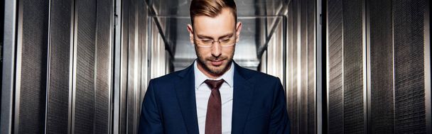 πανοραμική φωτογραφία του επιχειρηματία σε γυαλιά κοντά σε ράφια διακομιστή  - Φωτογραφία, εικόνα