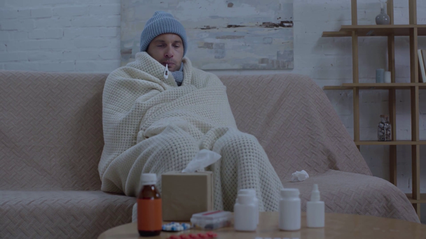hombre enfermo sentado cerca de la mesa con medicamentos, estornudos y medición de la temperatura
 - Metraje, vídeo
