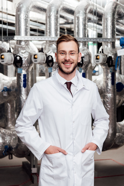 cheerful engineer in white coat standing with hands in pockets  - Photo, Image