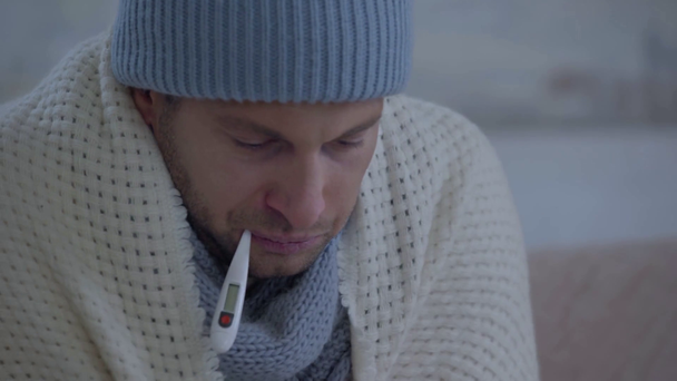 chory człowiek wycierający nos serwetką i mierzący temperaturę - Materiał filmowy, wideo