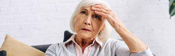 panoramic shot of senior woman having headache in apartment  - Foto, afbeelding