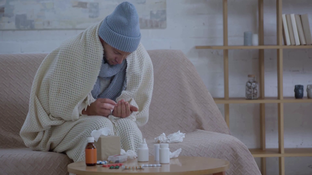 thick man sitting on sofa, wrapping in blanket and taking pills - Footage, Video