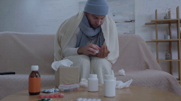 hombre enfermo sentado cerca de la mesa con medicamentos y tomando pastillas
 - Imágenes, Vídeo