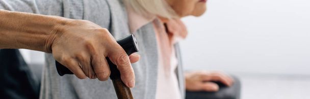 panoramic shot of senior woman with wooden cane in apartment  - Photo, Image