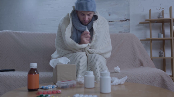 Kranker Mann sitzt mit Medikamenten am Tisch und benutzt Nasenspray - Filmmaterial, Video